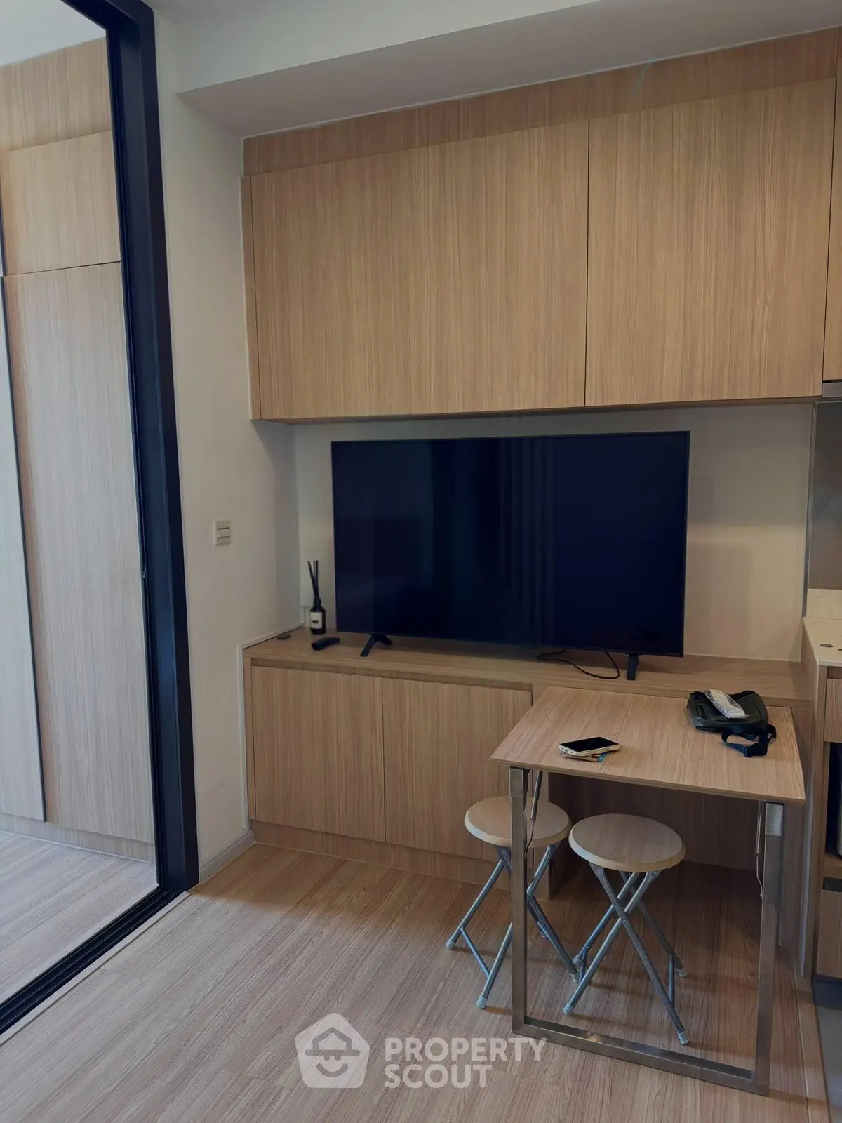 Modern compact living room with sleek wooden cabinetry and flat-screen TV, perfect for urban living.