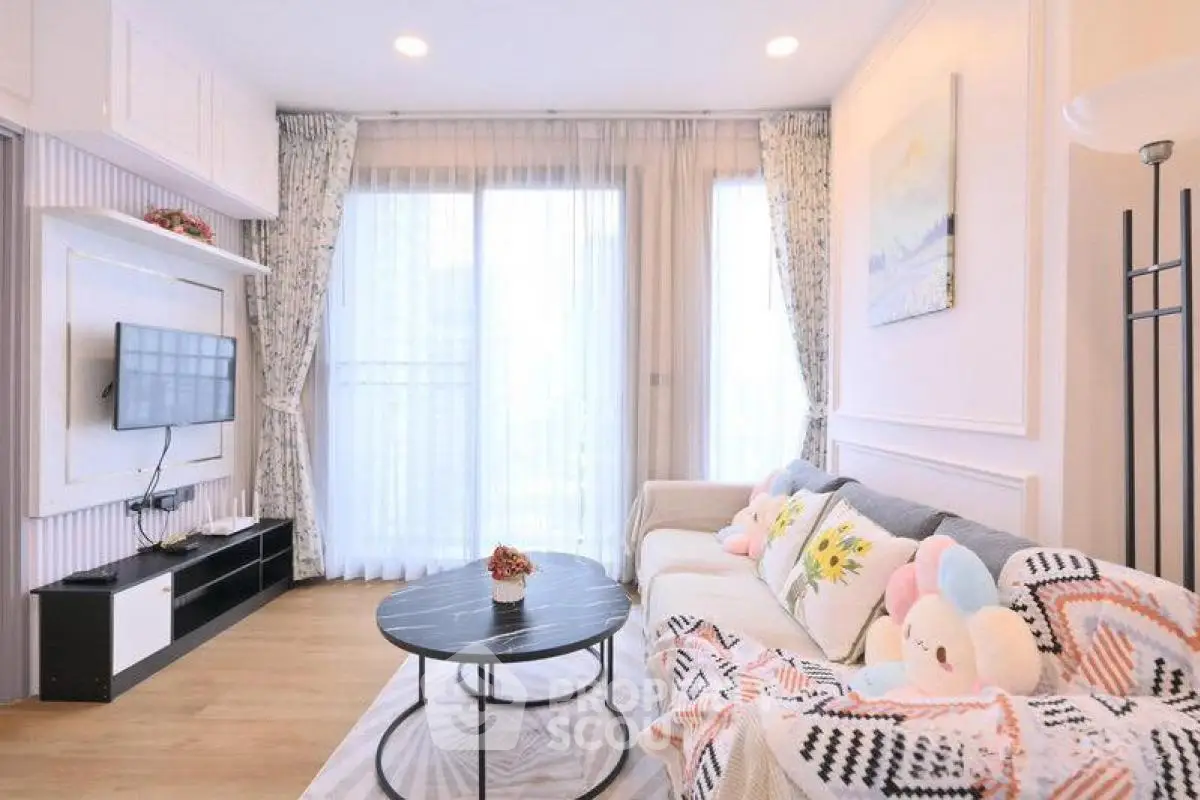 Charming living room with cozy decor and natural light, featuring a modern TV setup and plush seating.