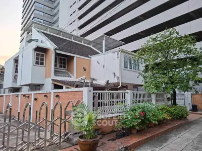 Charming urban house with garden, nestled between modern high-rise buildings, offering a unique blend of city and tranquility.