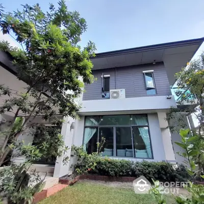 Modern two-story house with lush garden and large windows