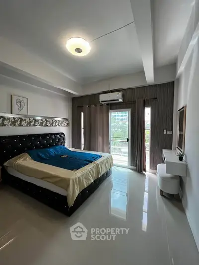Spacious bedroom with modern decor and balcony access in a stylish apartment.