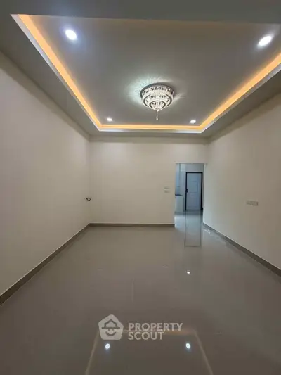 Spacious empty room with elegant ceiling lights and glossy tiled floor, perfect for customization.