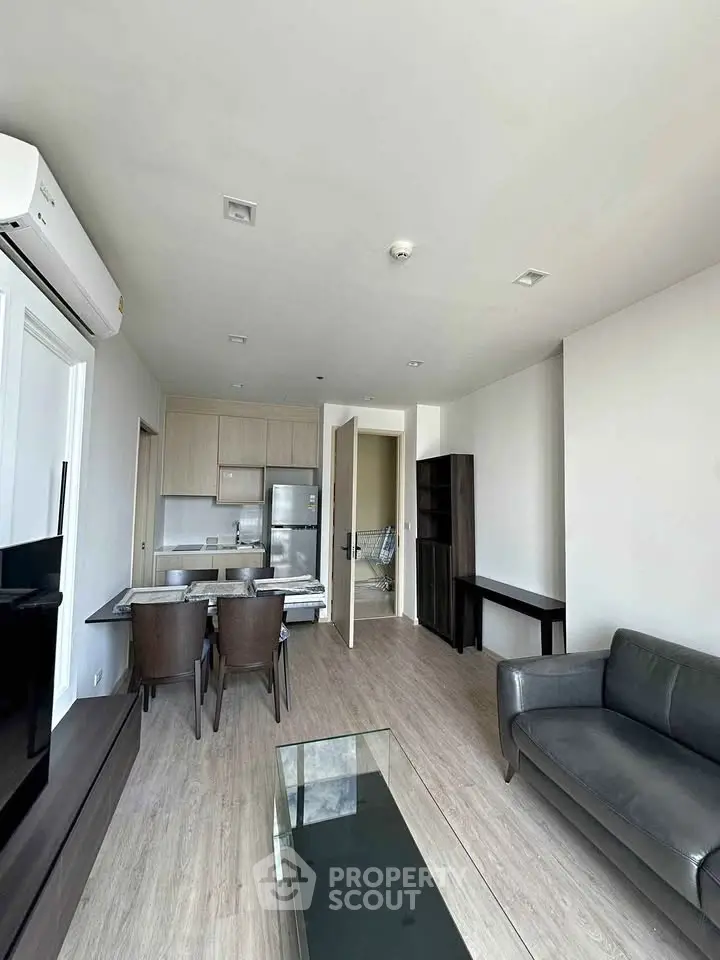 Modern living room with open kitchen, sleek furniture, and natural light in a contemporary apartment.