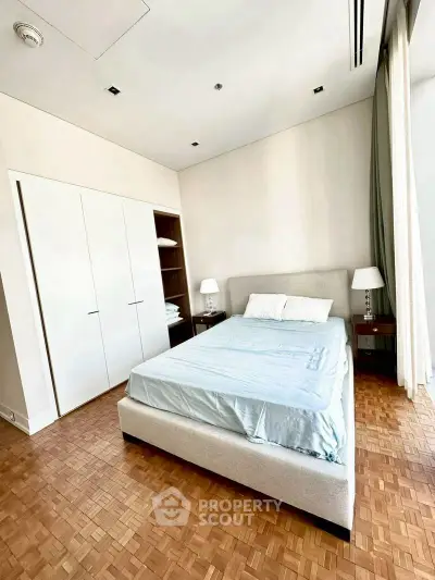 Spacious bedroom with parquet flooring and modern furnishings in a luxury apartment.
