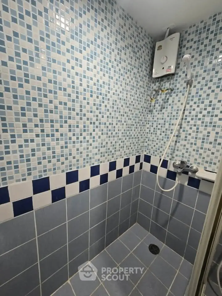 Modern bathroom with blue mosaic tiles and electric shower heater