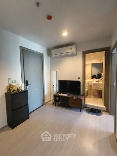 Modern apartment interior with TV and air conditioning, leading to bathroom.