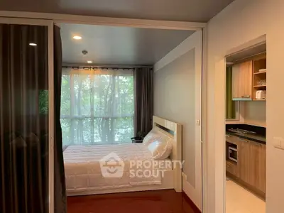 Cozy bedroom with large window and adjacent modern kitchen in stylish apartment.