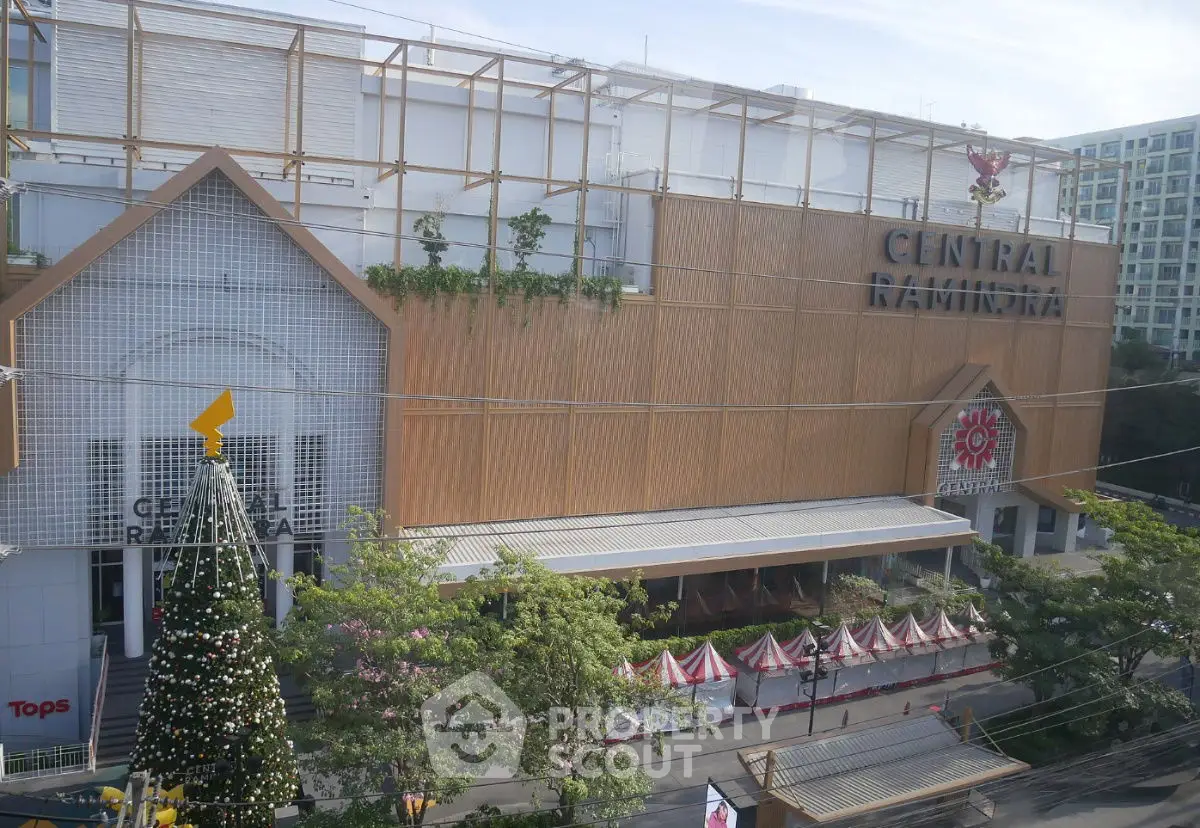 Modern shopping mall exterior with festive decorations and lush greenery.