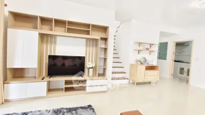 Spacious modern living room with stylish wooden furniture and sleek staircase