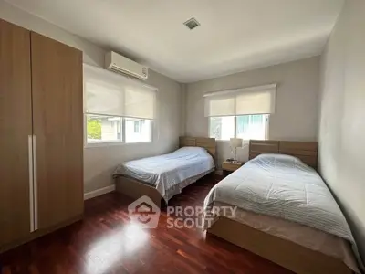 Cozy bedroom with twin beds and wooden flooring, perfect for a serene retreat.