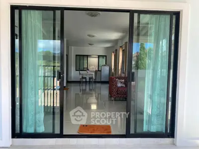 Spacious living room with sliding glass doors and elegant curtains, offering a seamless indoor-outdoor flow.