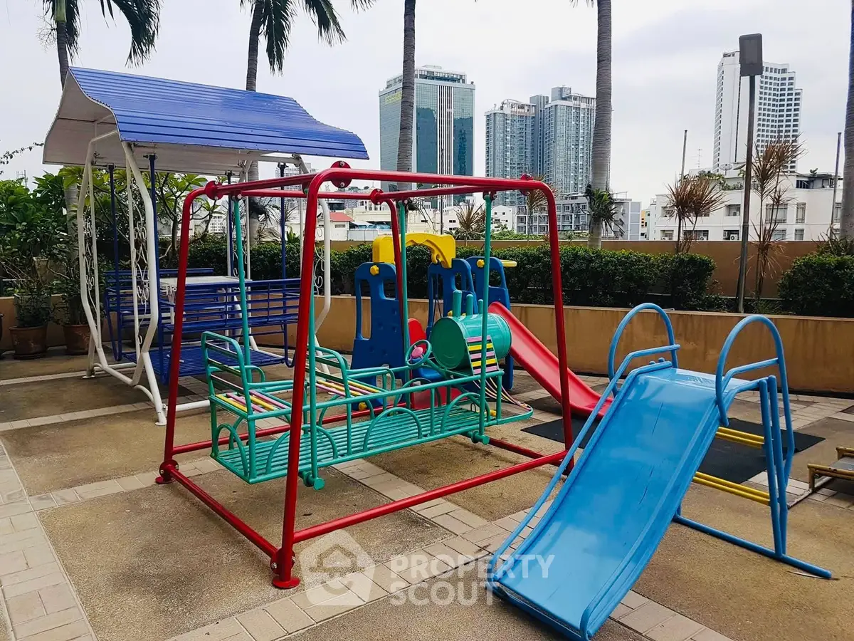 Vibrant playground area in urban residential complex with city skyline view.
