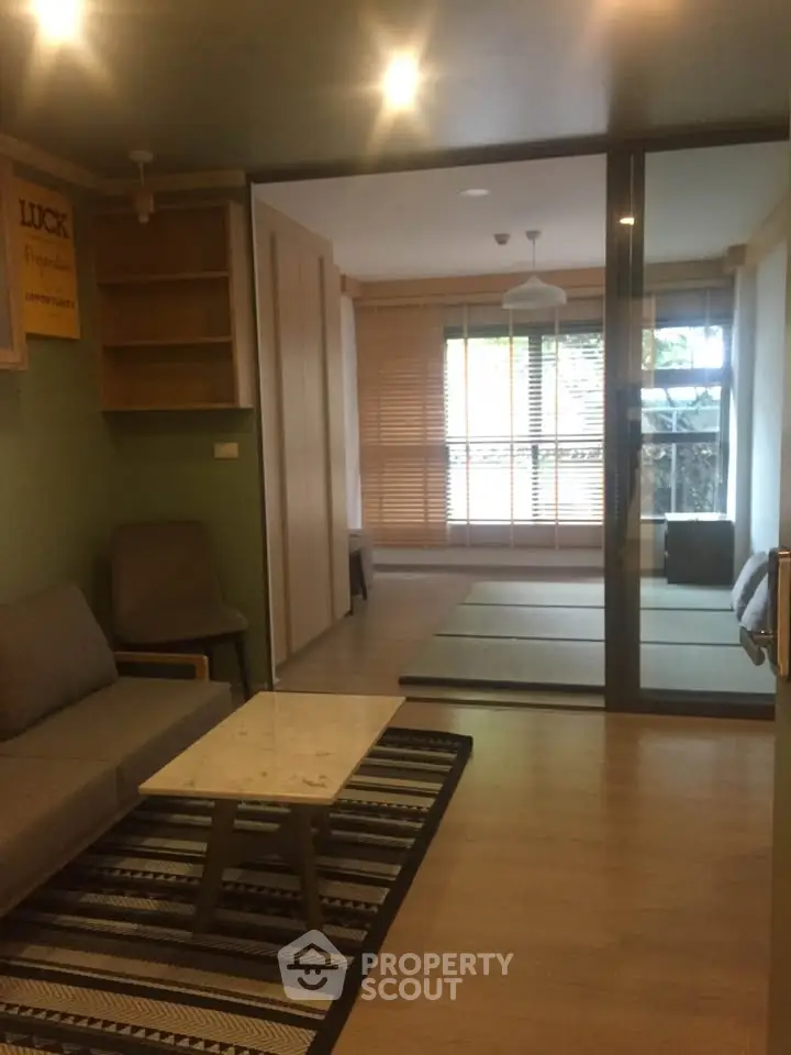 Modern living room with glass partition and cozy seating area in stylish apartment.