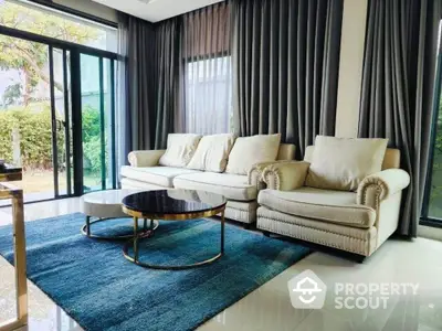 Luxurious living room with elegant sofa and modern decor, featuring large windows and lush garden view.