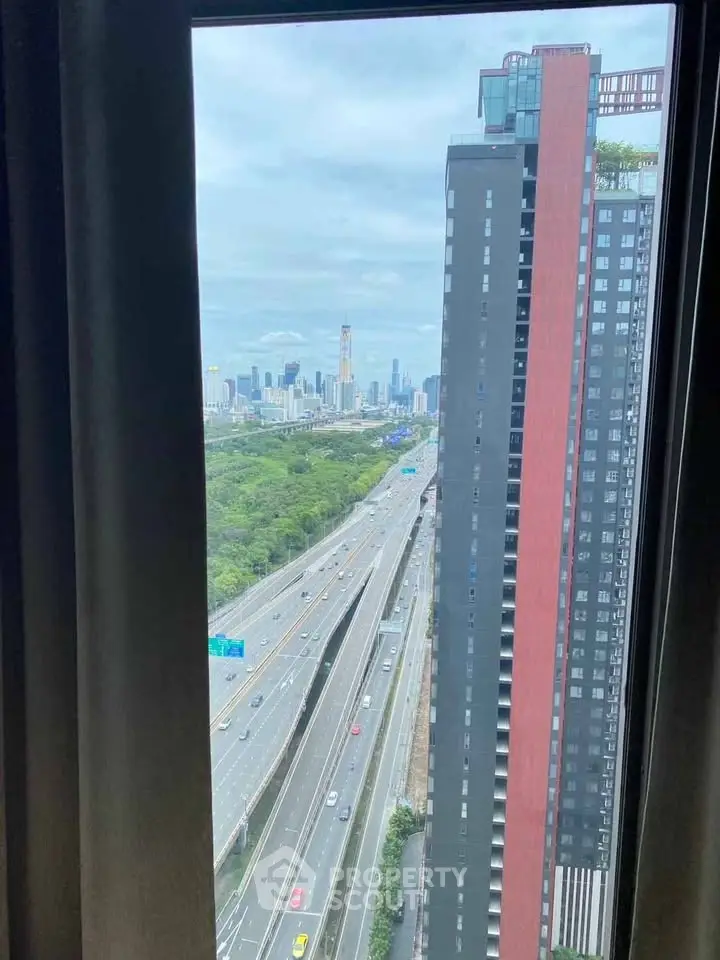 Stunning cityscape view from high-rise apartment window overlooking highway and skyline.