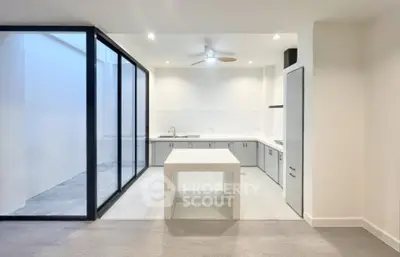 Modern kitchen with sleek design and open layout, featuring large glass doors and minimalist decor.