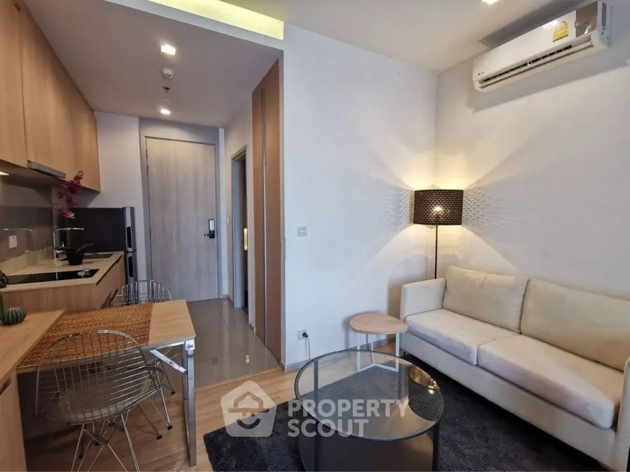 Modern open-layout living room with kitchen, featuring stylish furniture and ambient lighting.