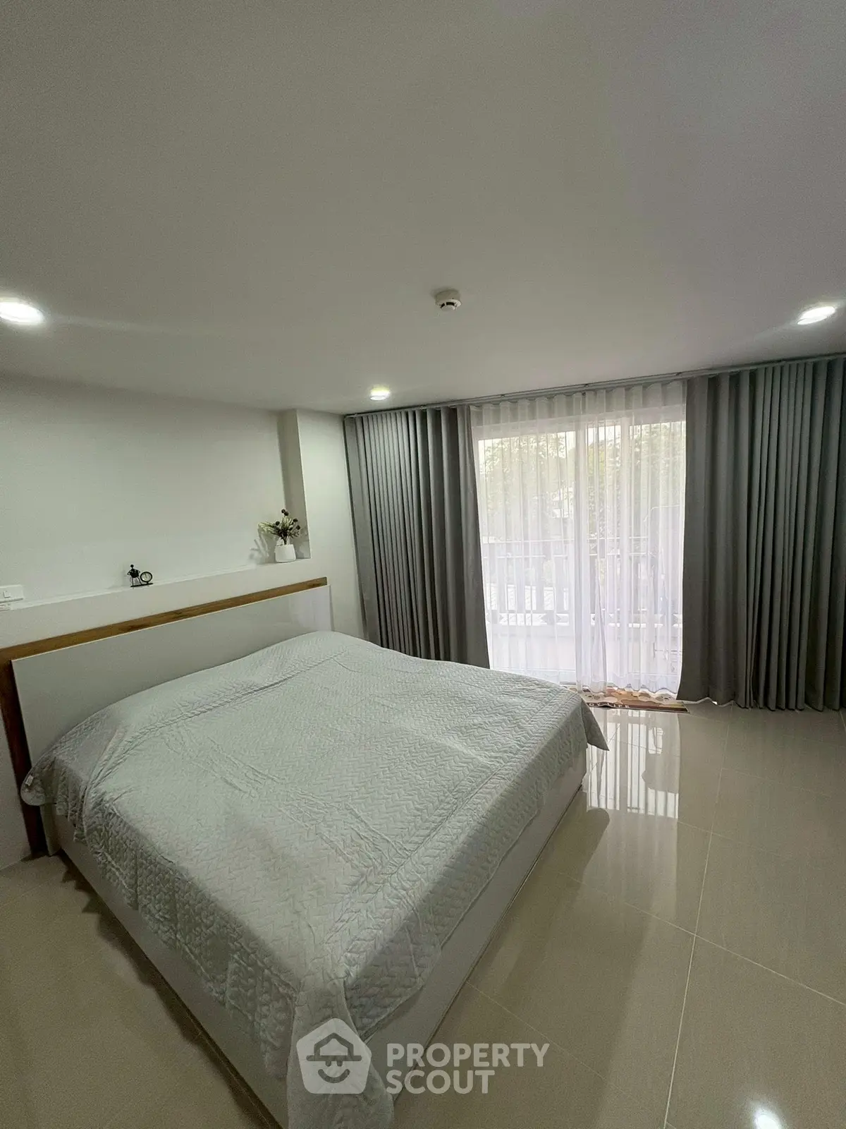 Spacious bedroom with modern decor and large window for natural light