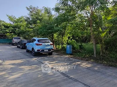 Spacious parking area surrounded by lush greenery and parked cars.