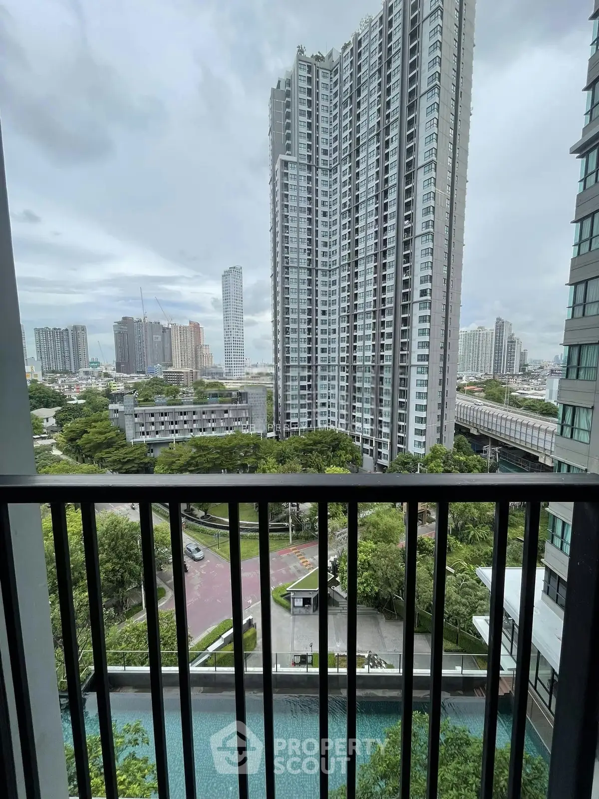 Stunning cityscape view from a high-rise balcony overlooking lush greenery and modern architecture.