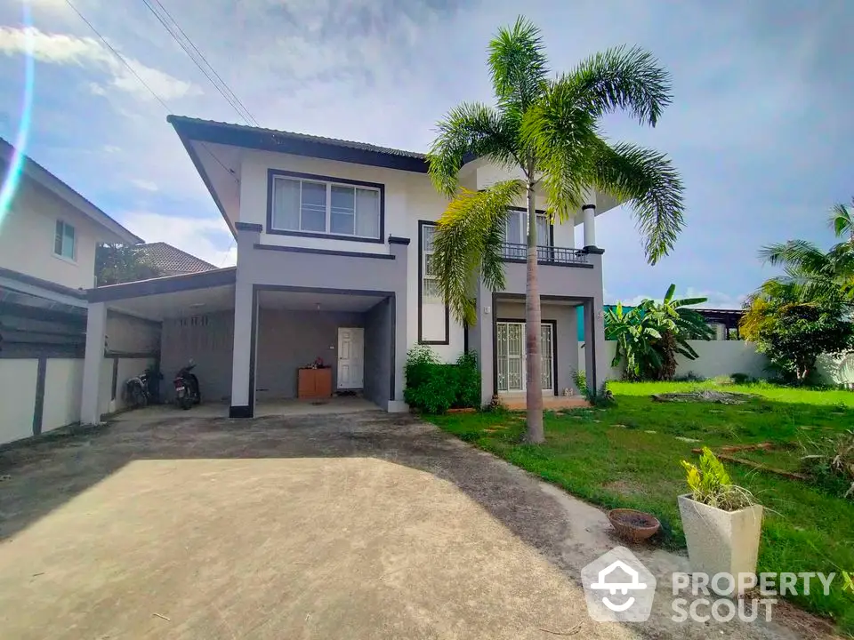 Spacious two-story house with lush garden and driveway in tropical setting