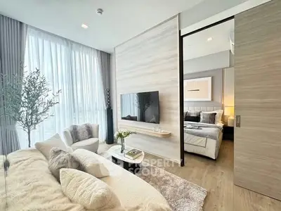 Modern living room with cozy seating and stylish decor, open to a chic bedroom.