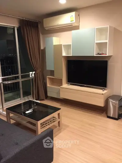 Modern living room with sleek furniture and large TV, featuring a stylish open layout and balcony access.