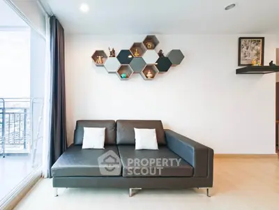 Modern living room with sleek black sofa and hexagonal wall shelves, adjacent to a balcony with city view.
