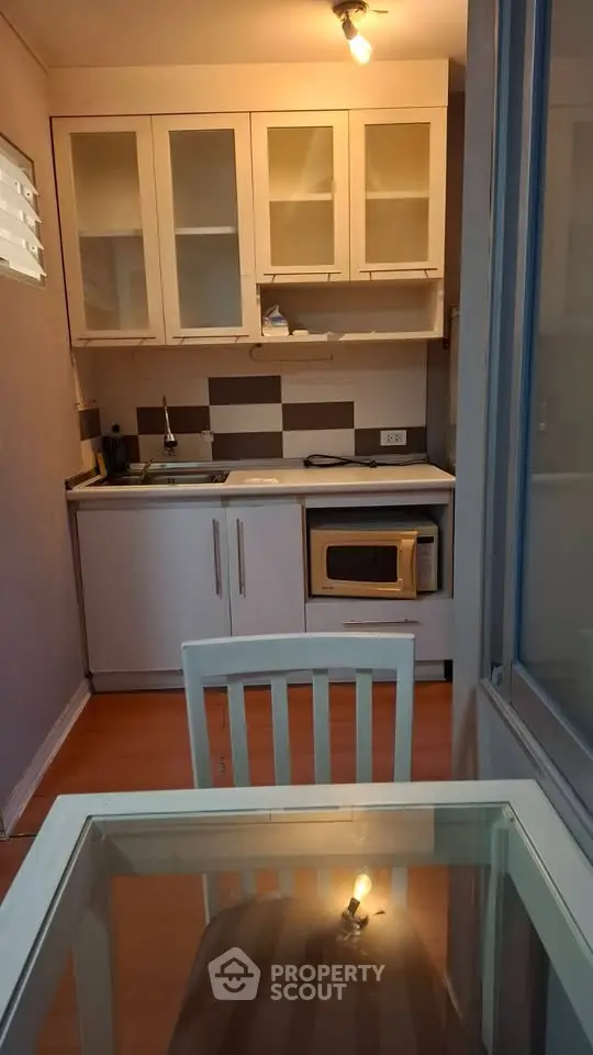 Cozy compact kitchen with modern appliances and dining area in a stylish apartment.