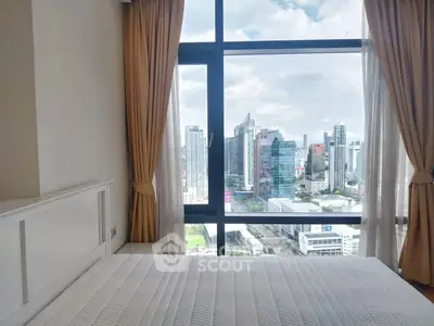 Luxurious bedroom with stunning city skyline view from floor-to-ceiling windows.