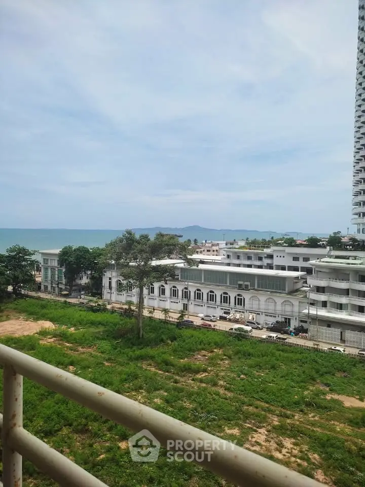 Stunning coastal view from a high-rise balcony overlooking lush greenery and ocean horizon.