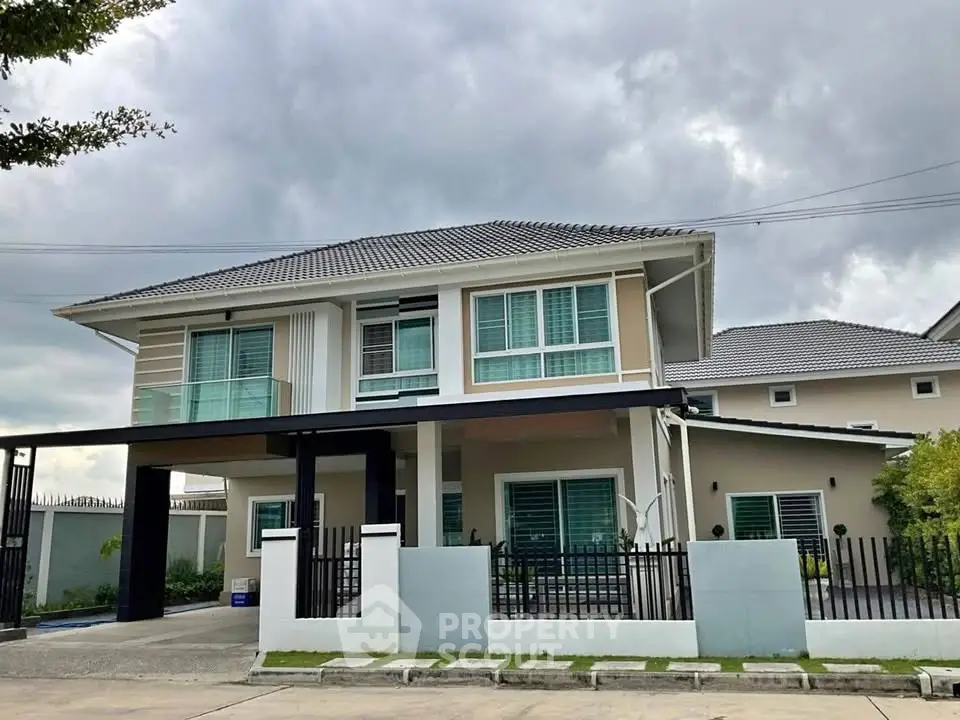 Modern two-story house with sleek design and spacious driveway under cloudy skies.