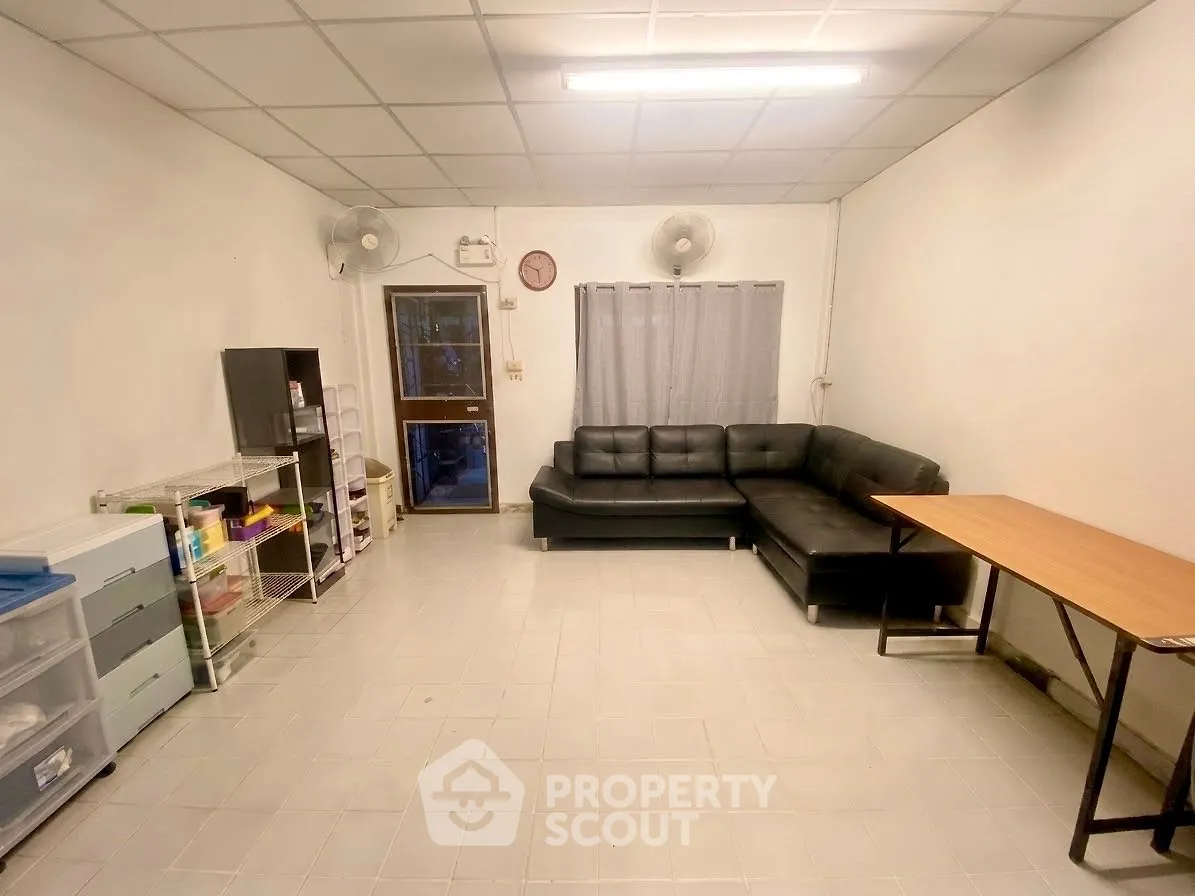 Spacious living room with black sectional sofa and minimalist decor.