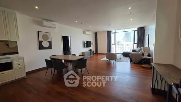 Spacious modern living room with wooden floors and city view, perfect for urban living.