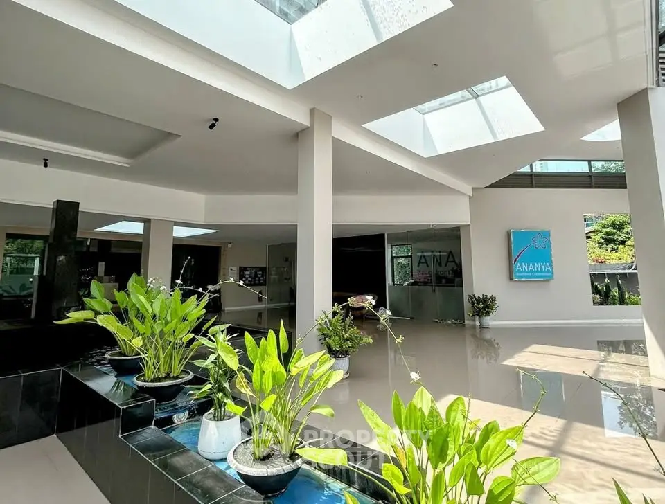 Modern building entrance with skylights and lush indoor plants