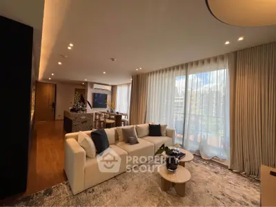 Luxurious open-plan living room with elegant decor and large windows leading to a balcony.