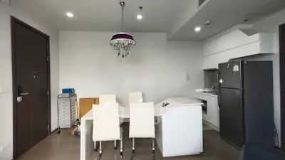 Modern kitchen with dining area featuring sleek white cabinetry and contemporary chandelier.