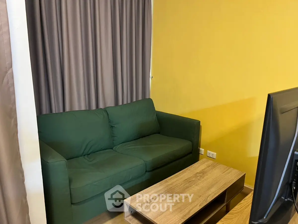 Cozy living room with green sofa and modern wooden coffee table.