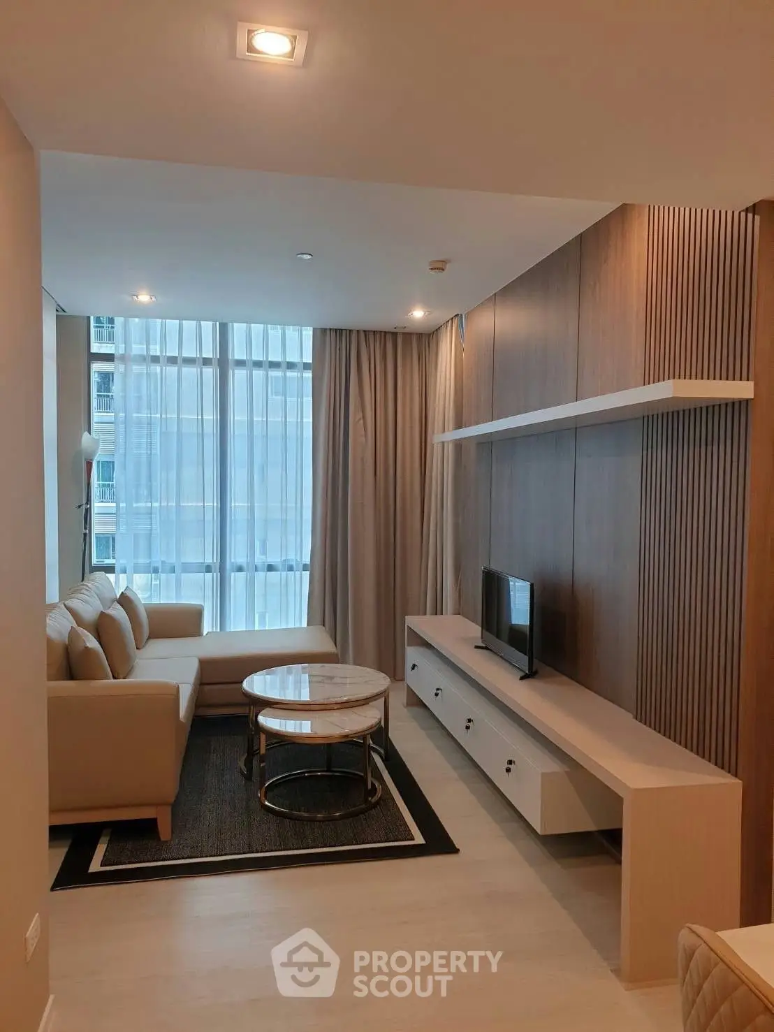 Modern living room with sleek furniture and large window offering natural light.