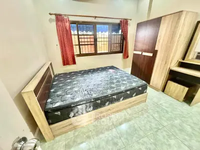 Cozy bedroom with modern wooden furniture and large window for natural light.