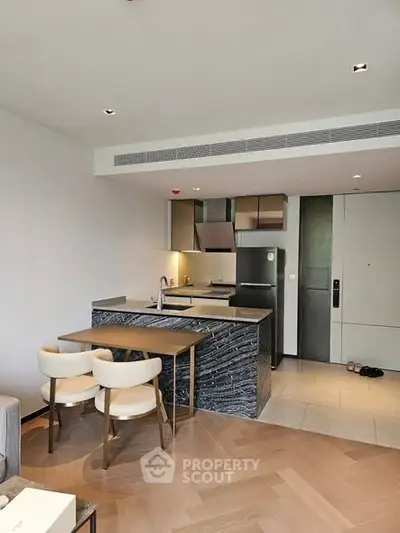 Modern kitchen with sleek design and dining area in open layout apartment.