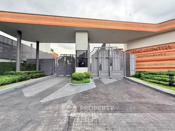 Modern gated entrance of luxury residential property with sleek design and lush landscaping.