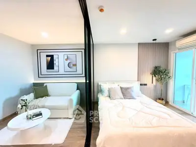 Modern studio apartment with stylish decor, featuring a cozy living area and comfortable bedroom separated by glass partition.