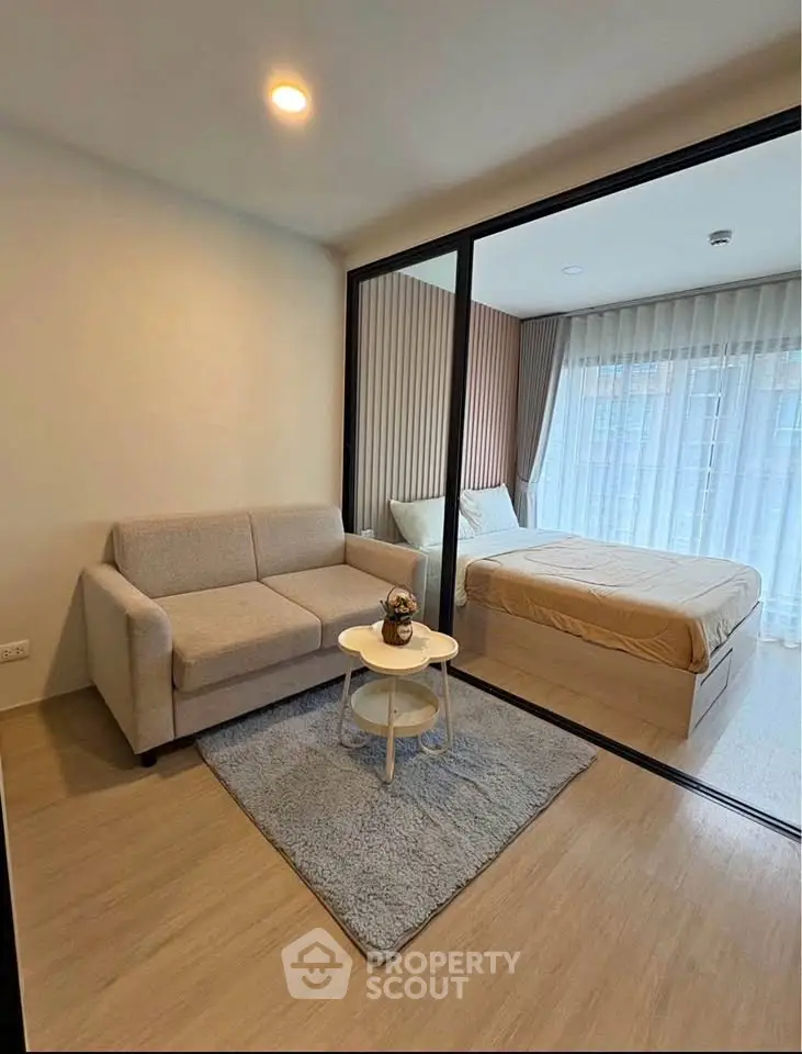 Modern studio apartment with cozy living area and glass partitioned bedroom.