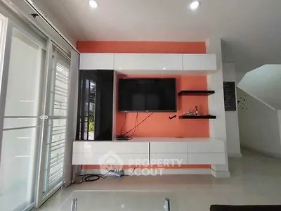 Modern living room with sleek TV unit and bright orange accent wall