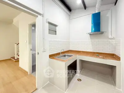 Modern kitchen with sleek design and open layout, featuring a stylish blue range hood and wooden countertops.