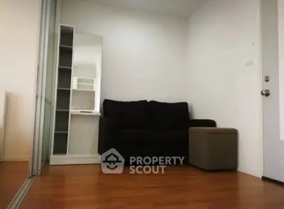 Cozy living room with dark sofa, mirrored closet, and wooden flooring