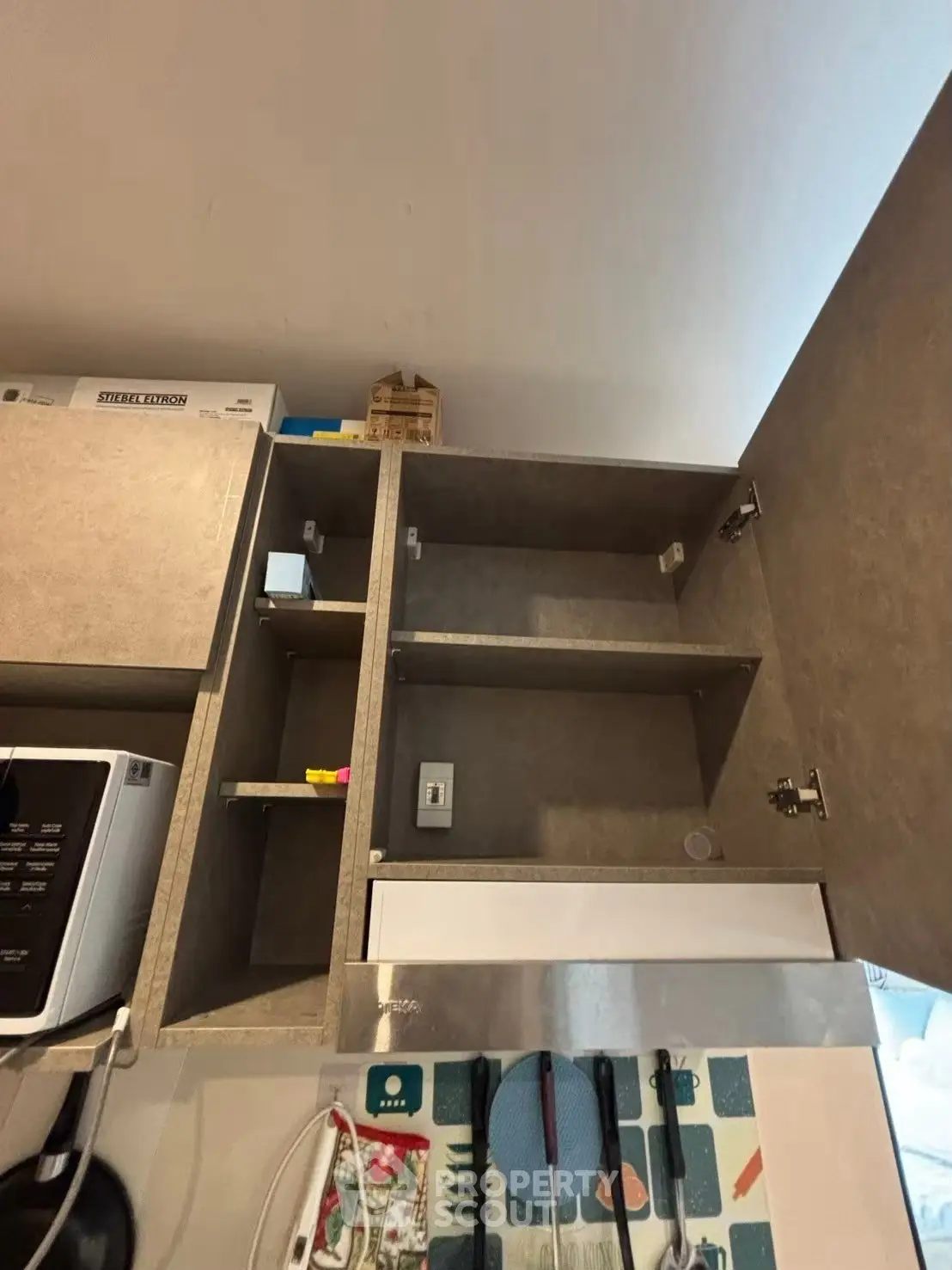 Modern kitchen with open cabinets and microwave, showcasing efficient storage solutions.