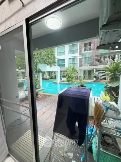 Stunning poolside view from modern apartment with glass doors and lush greenery.