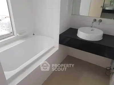 Modern bathroom with sleek black countertop and built-in bathtub in a bright setting.